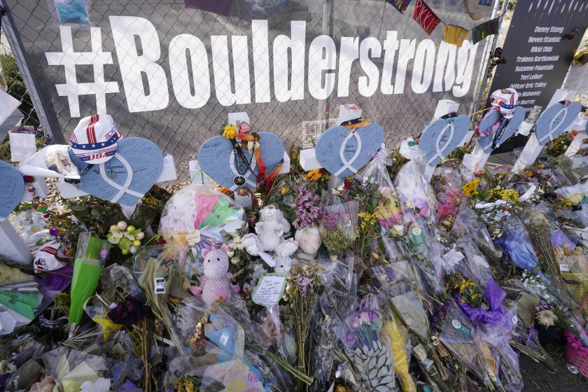 Tributes stand near the temporary fence surrounding the parking lot in front of a King Soopers grocery store in which 10 people died in a late March mass shooting Friday, April 9, 2021, in Boulder, Colo. (AP Photo/David Zalubowski)