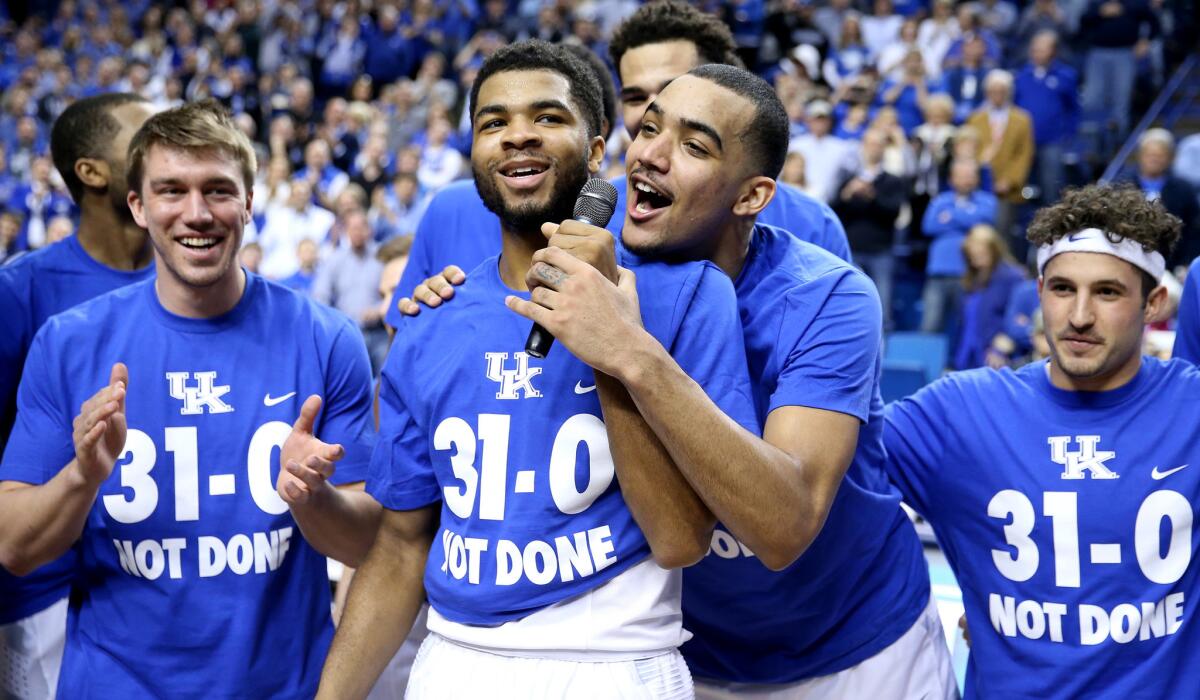 Trey Lyles takes the microphone from Andrew Harrison as the Kentucky players celebrate their victory over Florida, and unbeaten regular season, with fans on Saturday.