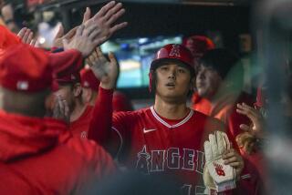 Los Angeles Angels' Shohei Ohtani gets high-fives from teammates in the dugout.