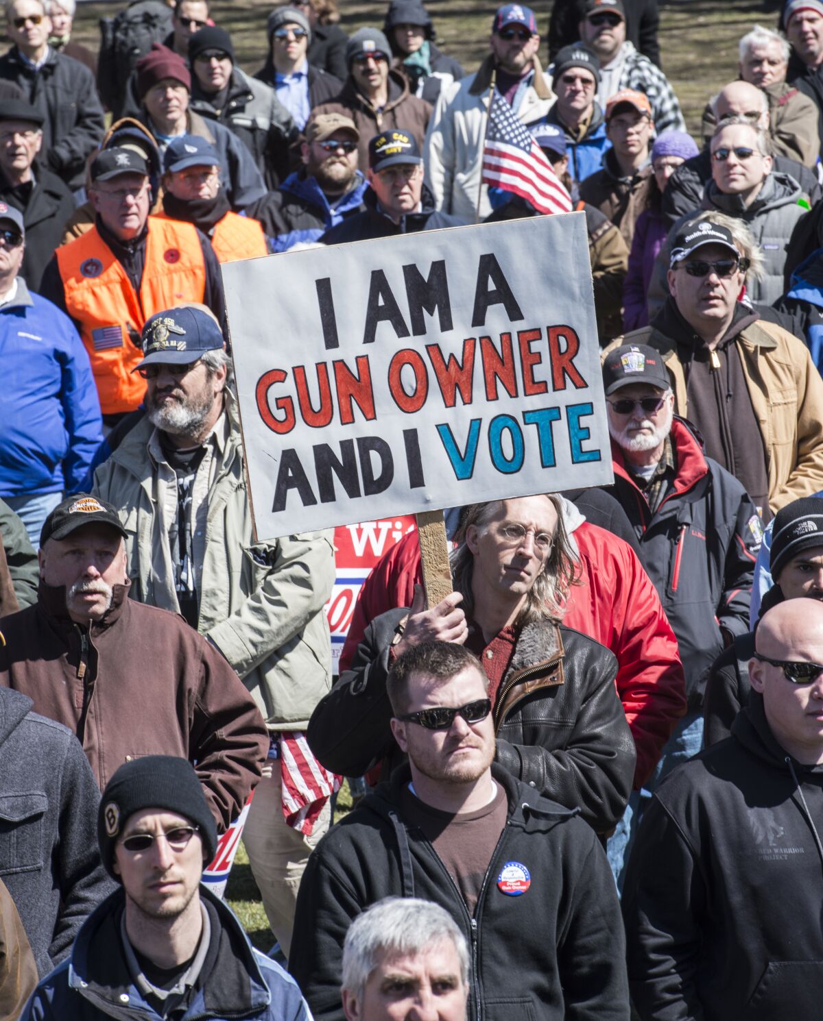 People at a pro-gun rally in Boston, with one person holding a sign that reads 'I am a gun owner and I vote'