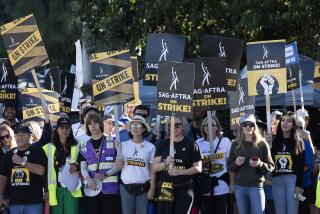 A large group of demonstrators carrying picket signs that read, "SAG-AFTRA on Strike!"