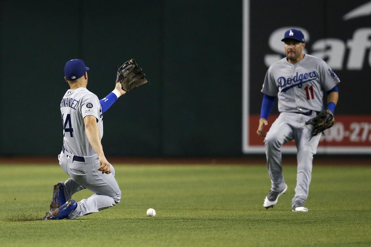 A pop fly hit by Arizona's Eduardo Escobar between Dodgers second baseman Enrique Hernandez, left, and center fielder A.J. Pollock for a single during the fourth inning of Thursday's loss.