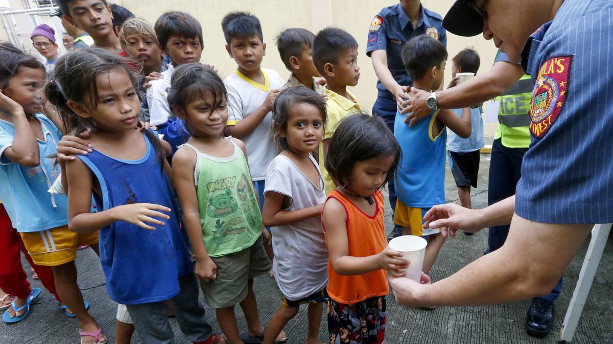 Manila police hand out rice porridge to children in the coastal community of Baseco as they evacuate.