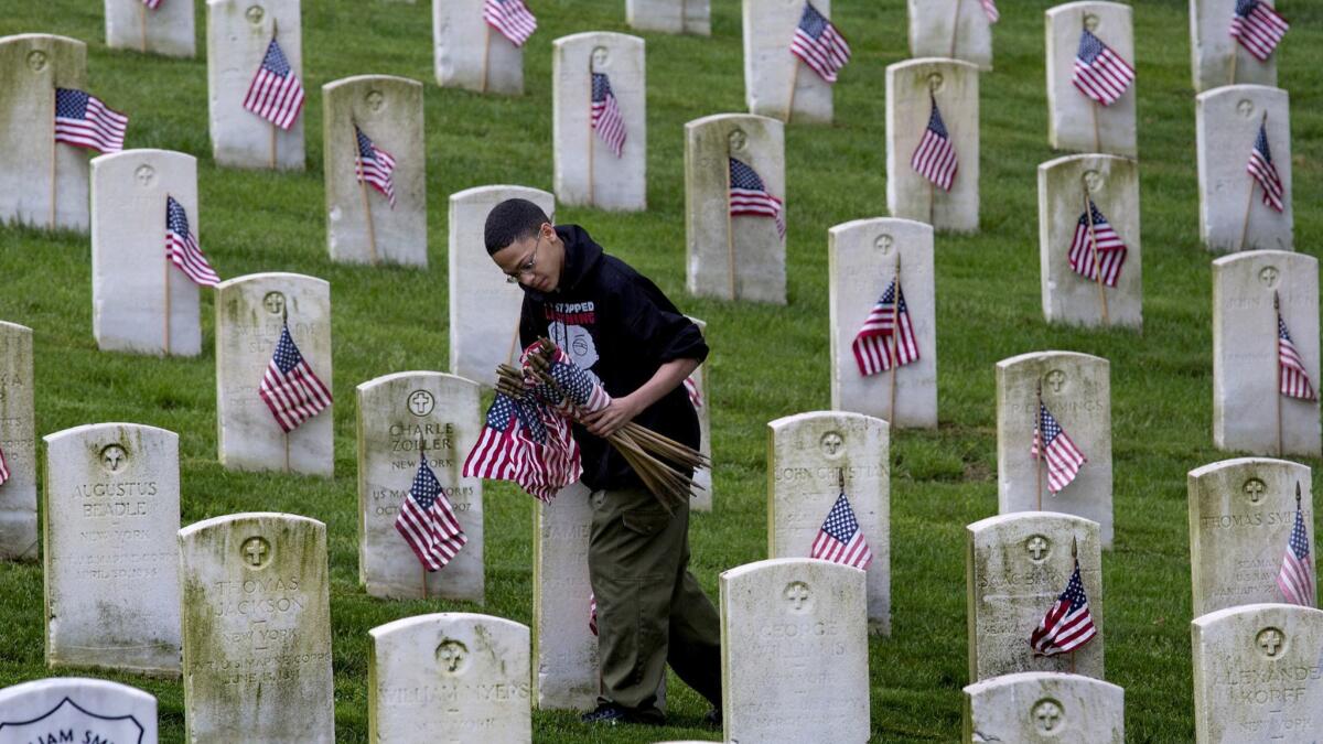 A Boy Scout places American flags on gravesites for veterans of the Civil War, American Revolution, Spanish-American War, Korean and Vietnam wars at the Cypress Hills National Cemetery in New York on May 25, 2013.