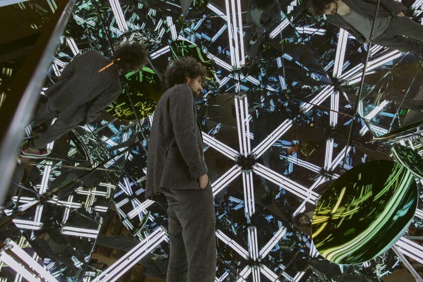 A man surrounded by lights and mirrors