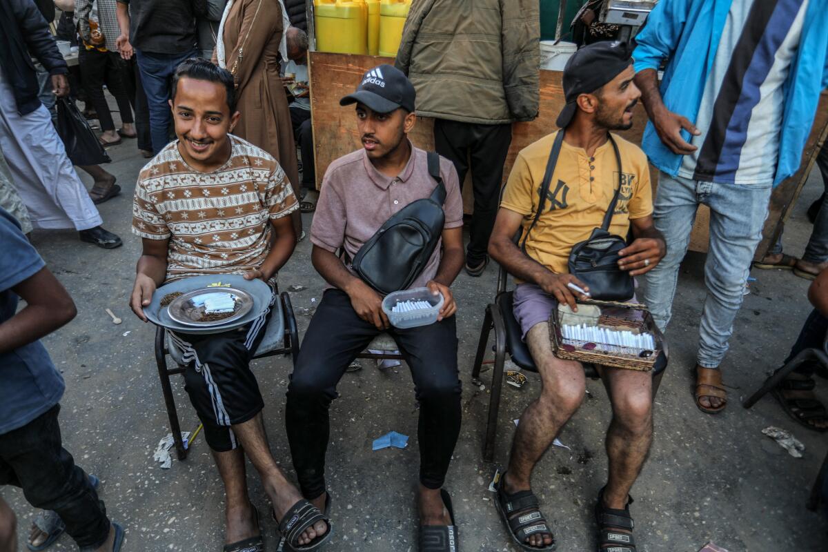 Três homens sentados seguram pratos contendo cigarros 