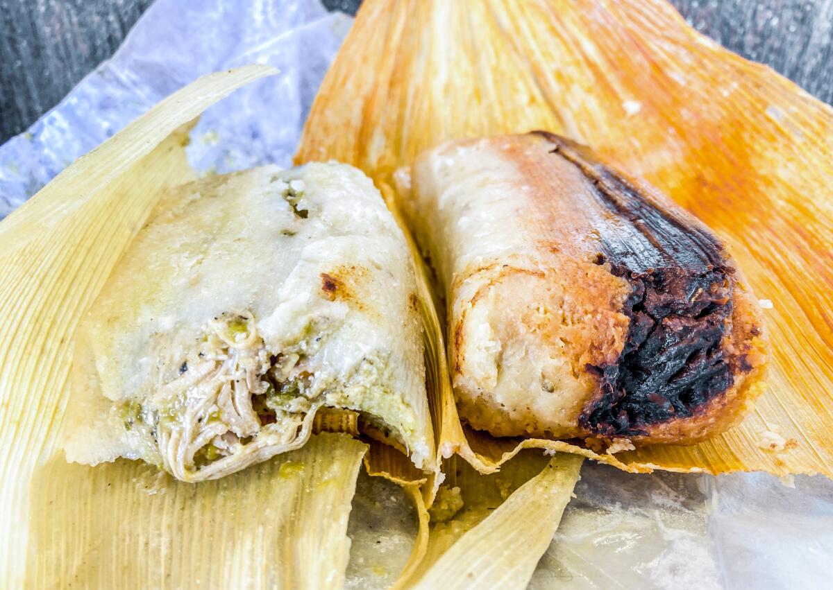 Two tamales, unwrapped, sitting on corn husks
