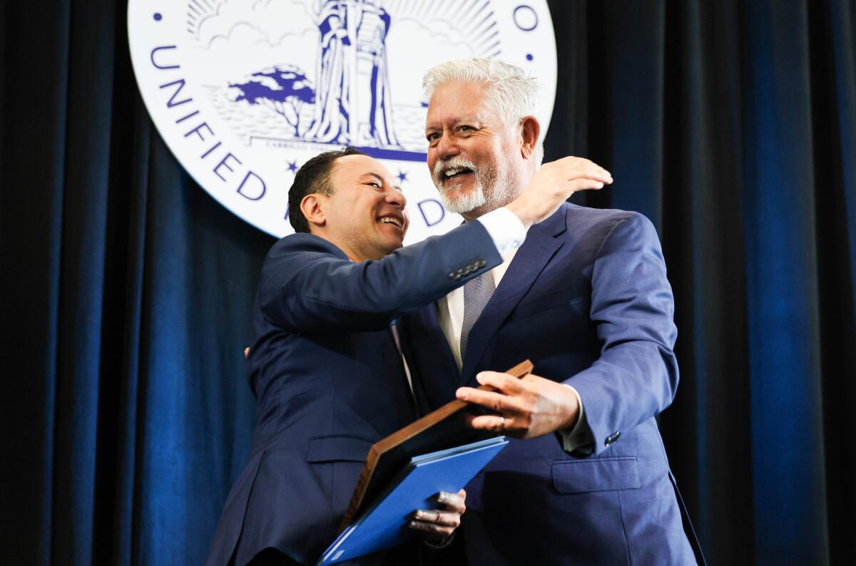 Rafael Castellanos and Frank Urtasun hug during the Port of San Diego's swearing in ceremony for its 2024 executive officers