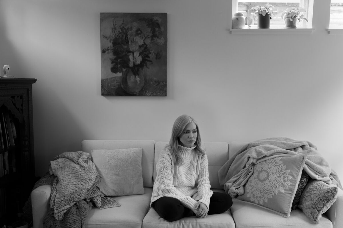 A woman sits cross-legged on a couch.