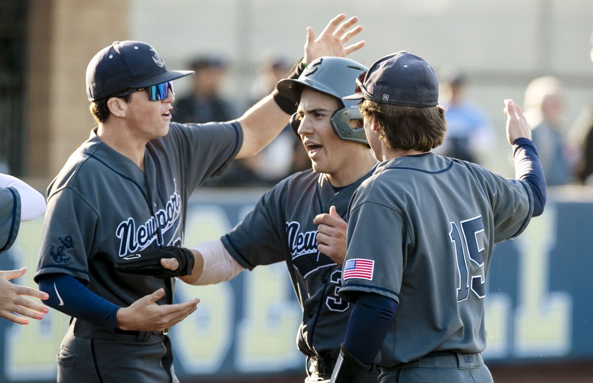 Newport Harbor's Lucas Perez, center, celebrates after scoring in the third inning during a Battle of the Bay baseball game.