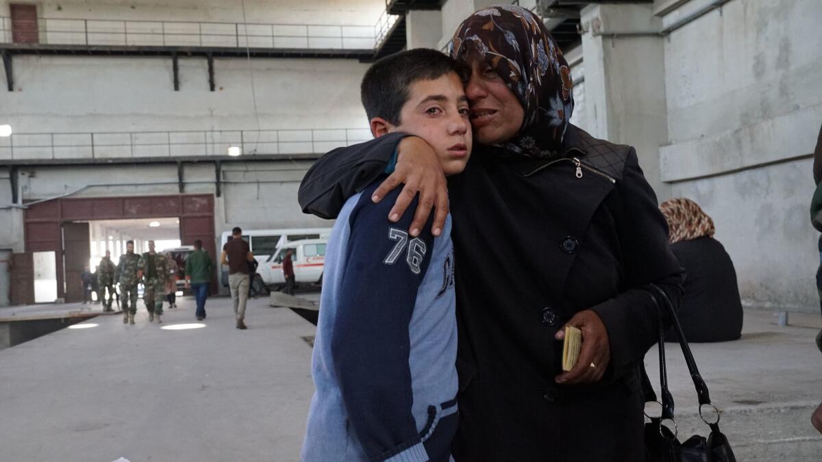 Relatives of slain victim Saeed Sheikh from the town of Fuah arrive at the abandoned industrial complex of Jibreen on the outskirts of eastern Aleppo, Syria, on April 16, 2017. At left, Ali Sheikh, 12, is hugged by his mother, Hanan al Hussein, 42.