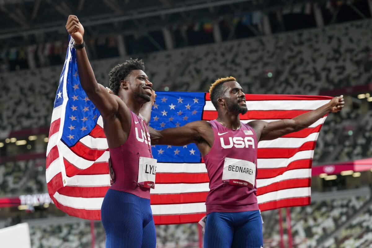 Kenneth Bednarek and Noah Lyles hold a U.S. flag.
