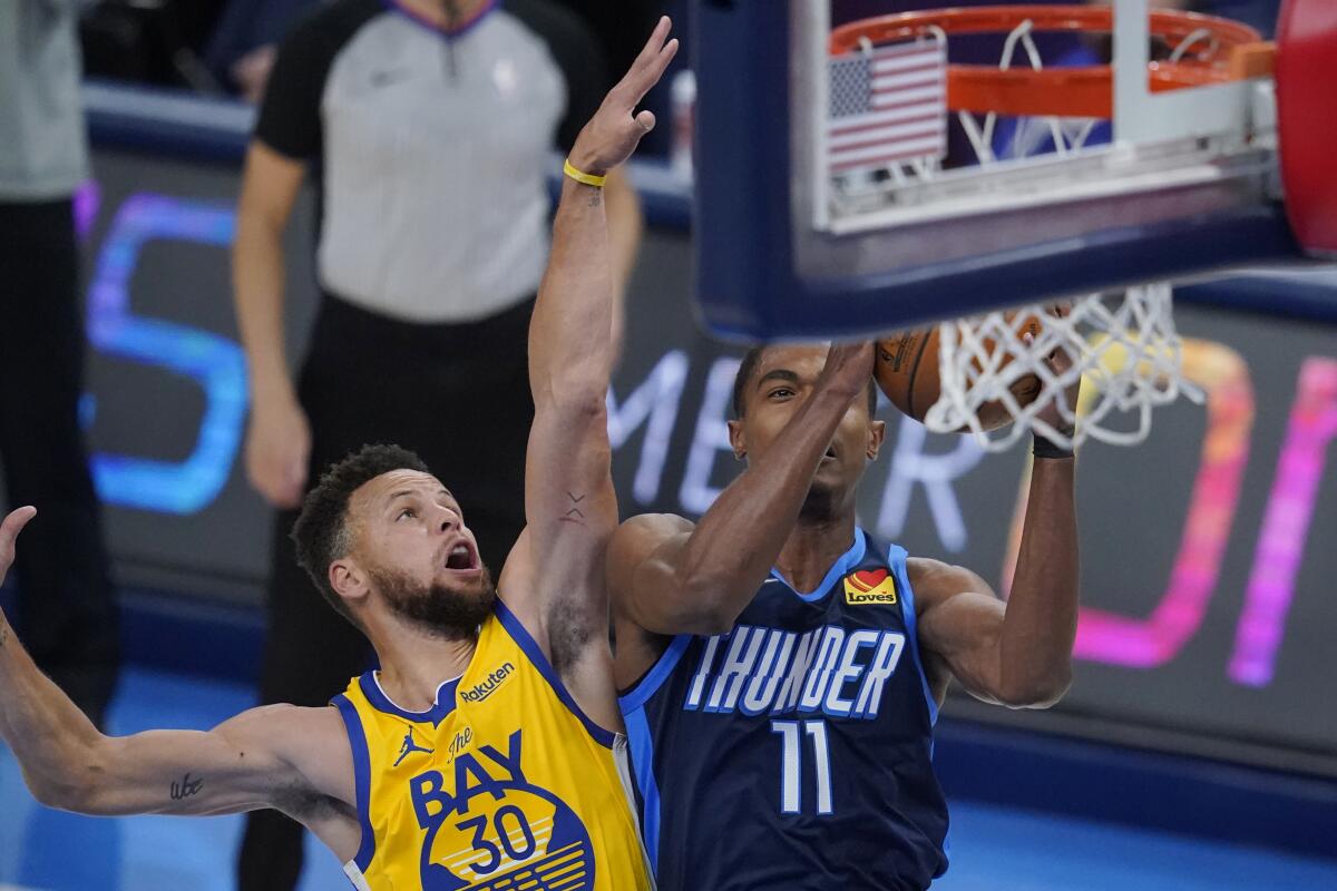 Oklahoma City Thunder guard Theo Maledon (11) shoots in front of Golden State Warriors guard Stephen Curry (30) in the first half of an NBA basketball game Wednesday, April 14, 2021, in Oklahoma City. (AP Photo/Sue Ogrocki)