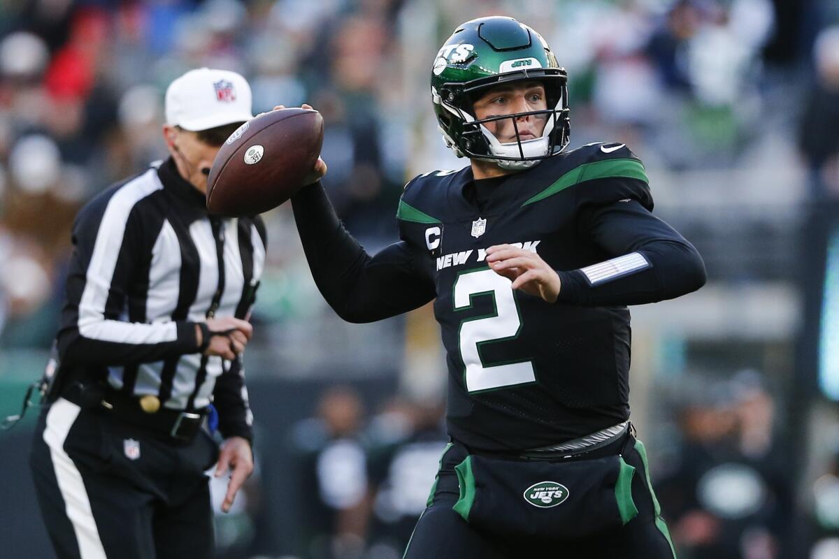New York Jets quarterback Zach Wilson passes while a referee watches from the side