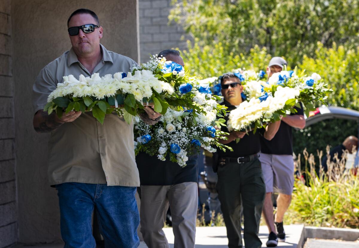 CHP officers and Riverside County deputies carry flowers to be placed in front of the CHP station in Riverside in memory of fallen Officer Andre Moye.