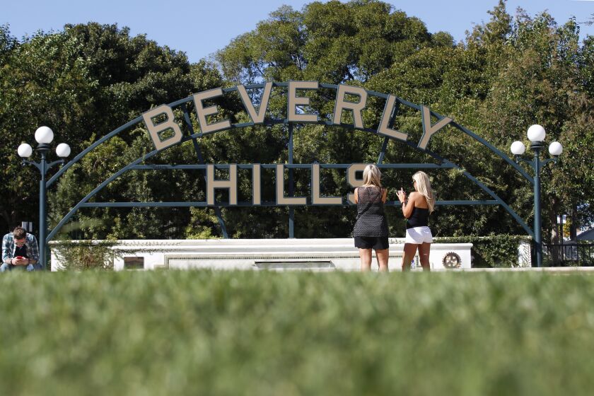 BEVERLY HILLS, CALIF. -- FRIDAY, OCTOBER 30, 2015: Tourists view their photos of the Beverly Hills sign in Beverly Gardens Park, Beverly Hills Friday, Oct. 30, 2015. Photos taken in Beverly Hills, Calif., on Oct. 30, 2015. The city of Beverly Hills and three other water suppliers face financial penalties for falling short of state water conservation mandates, officials said Friday. Statewide, Californians cut their urban water use in September by 26.1% compared with the same month in 2013, regulators said. The reduction was below the 27% decline recorded in August and the 31% savings in July. In addition to Beverly Hills, the cities of Indio and Redlands and the Coachella Valley Water District were issued a $61,000 penalty for failing to meet their conservation mandates, officials said. (Allen J. Schaben / Los Angeles Times)
