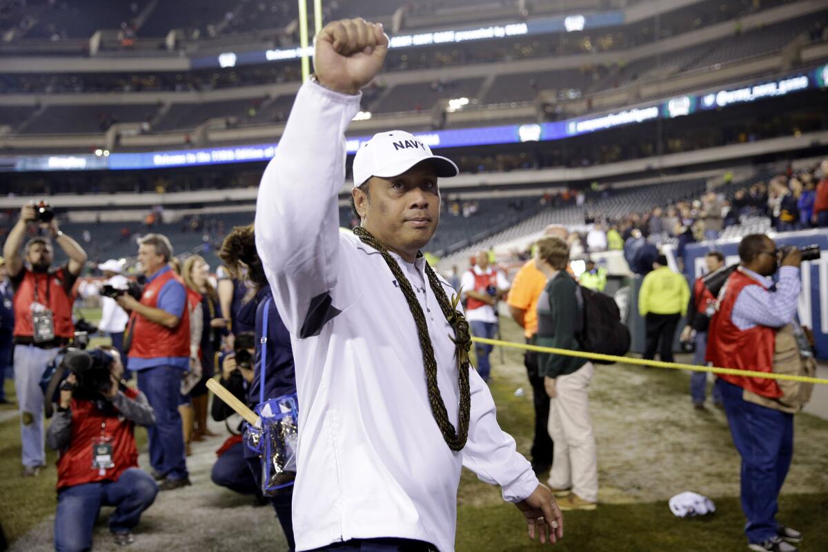 Navy Coach Ken Niumatalolo gestures to fans as he walks off the field after winning 21-17 over rival Army in Philadelphia.