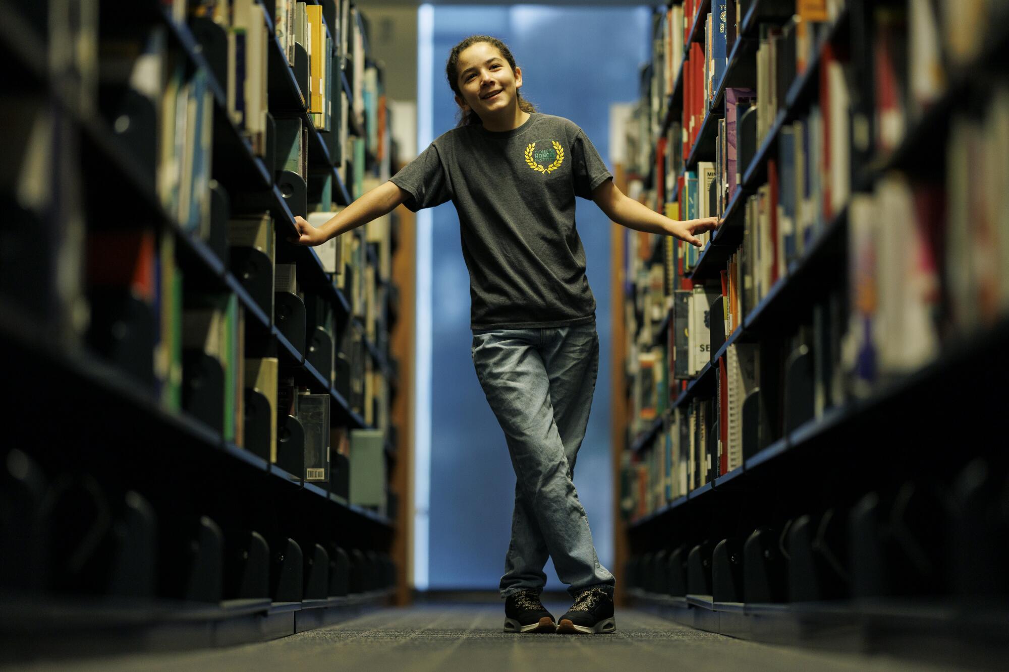 A student stands between two stacks of books.