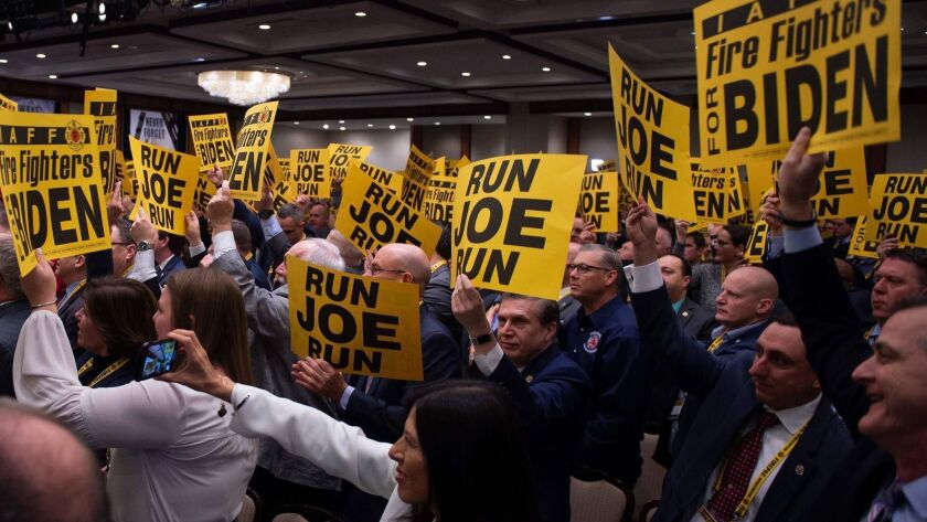 Audience members hold up signs urging him to run for president as former Vice President Joe Biden speaks March 12 at the International Assn. of Fire Fighters conference in Washington.