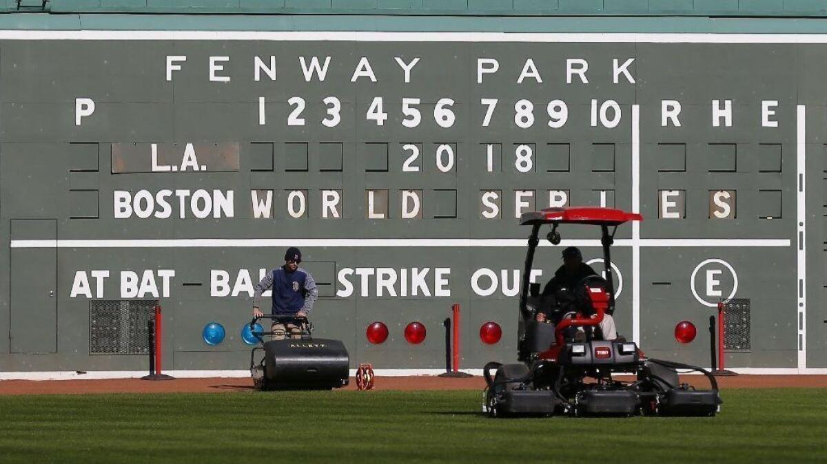 Groundskeepers mow the lawn in front of Fenway Park's left field scoreboard on Oct. 22.