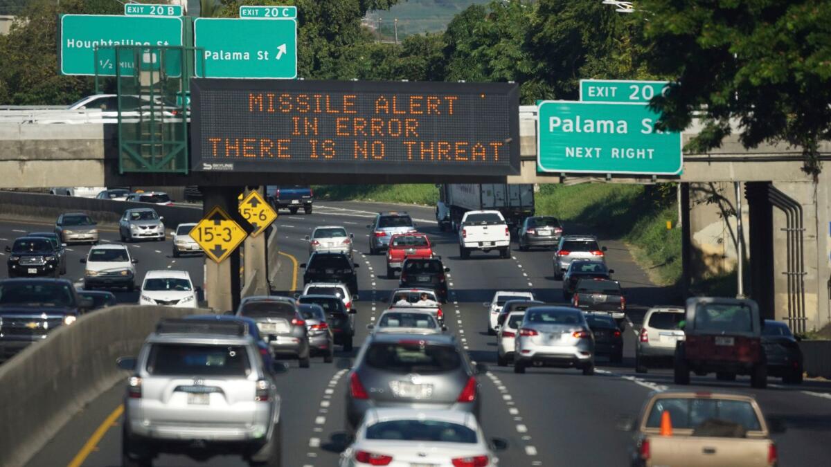 Cars drive past a highway sign in Honolulu on Saturday explaining that an earlier missile alert was sent in error.