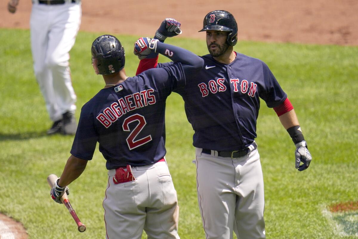 Boston Red Sox's J.D. Martinez, right, is greeted near home plate by Xander Bogaerts after hitting a solo home run off Baltimore Orioles starting pitcher Jorge Lopez during the third inning of a baseball game, Sunday, April 11, 2021, in Baltimore. (AP Photo/Julio Cortez)