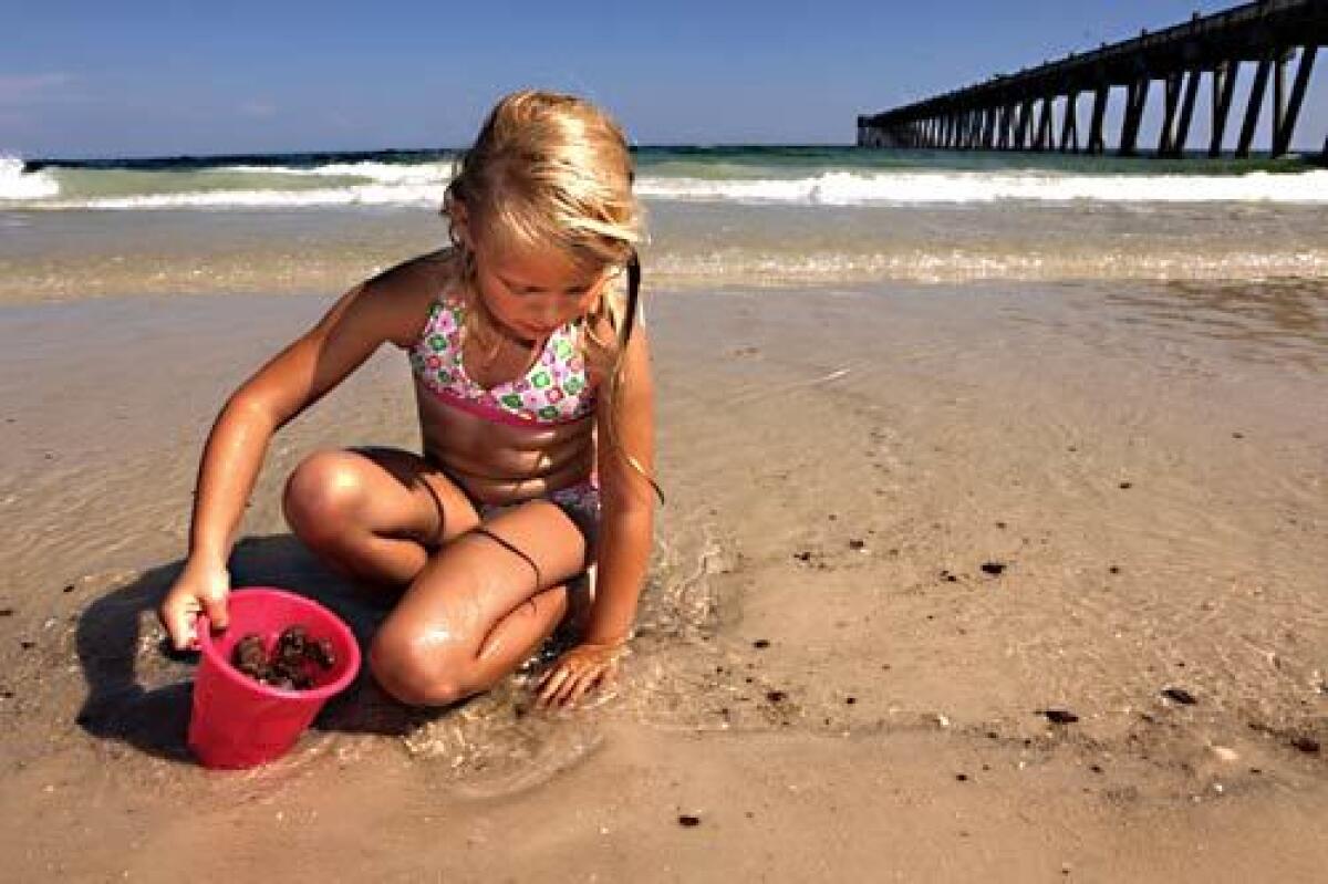 Mary-Kate Oldham, 6, of Tennessee puts tar balls in her sand bucket on Pensacola Beach, Fla. during a family vacation in June. "I think we'll just take [the kids] home and scrub them," said Holly Adkins, Mary-Kate's mother.