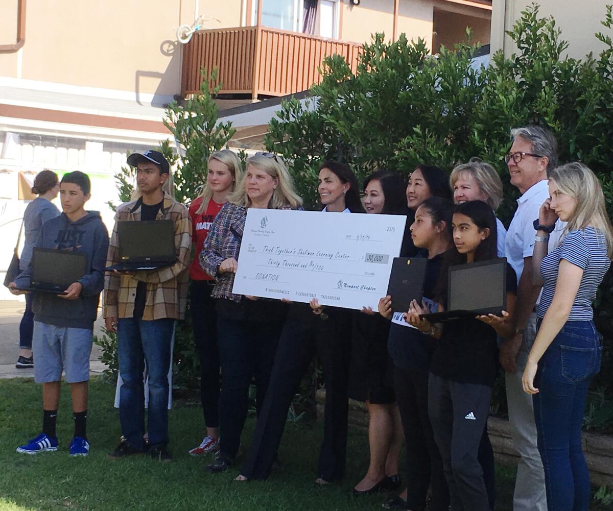 Members of the Newport Chapter of the National Charity League present a $30,000 check Wednesday to the Think Together Shalimar Learning Center for a new coding program.