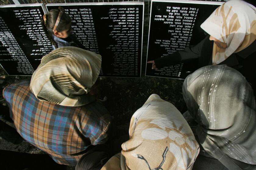Palestinian relatives of residents of the Arab village of Deir Yassin stand over plaques listing the names of more than 100 people killed by Irgun Lehi militants, a pre-state Israeli militant group, as they mark the 60th anniversary of the attack, at the site where the village stood in 1948, currently in Jerusalem, Thursday, April 10, 2008. (AP Photo/Ed Ou)