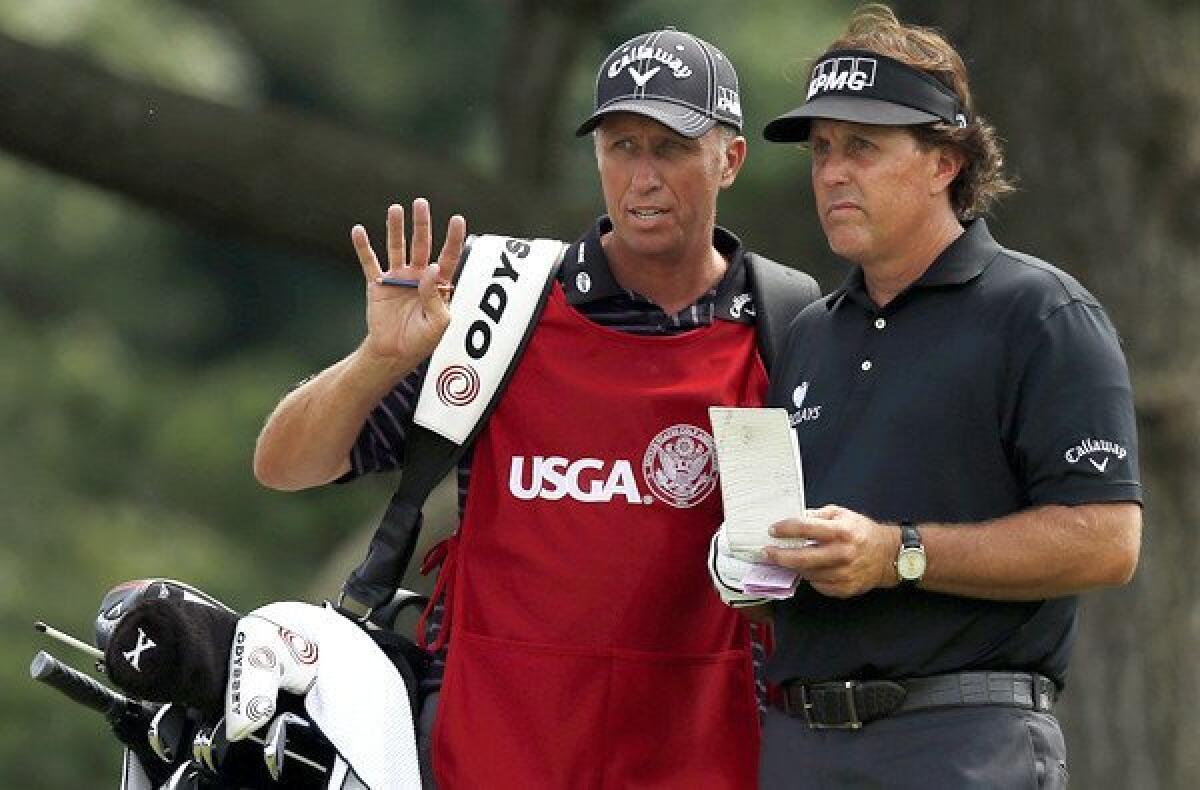 Phil Mickelson talks strategy with caddie Jim Mackay on the ninth hole at Merion Golf Club during the first round of the U.S. Open on Thursday.