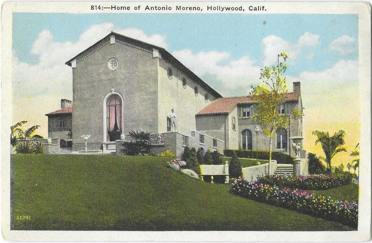 Antonio Moreno stands outside a large home with a manicured lawn and colorful flowerbeds.