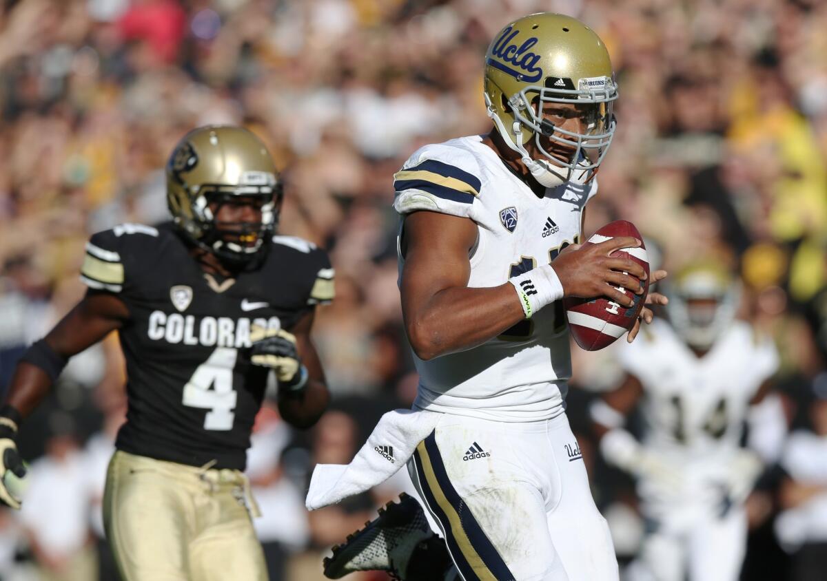 UCLA quarterback Brett Hundley scores the winning touchdown ahead of Colorado defensive back Chidobe Awuzie in the Bruins' 40-37 double-overtime victory over Colorado on Saturday.