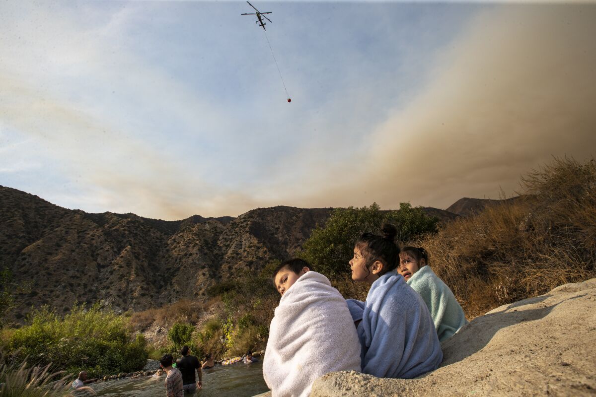 The Ranch2 fire burns nearby as three young children dry off  after swimming along the San Gabriel River 
