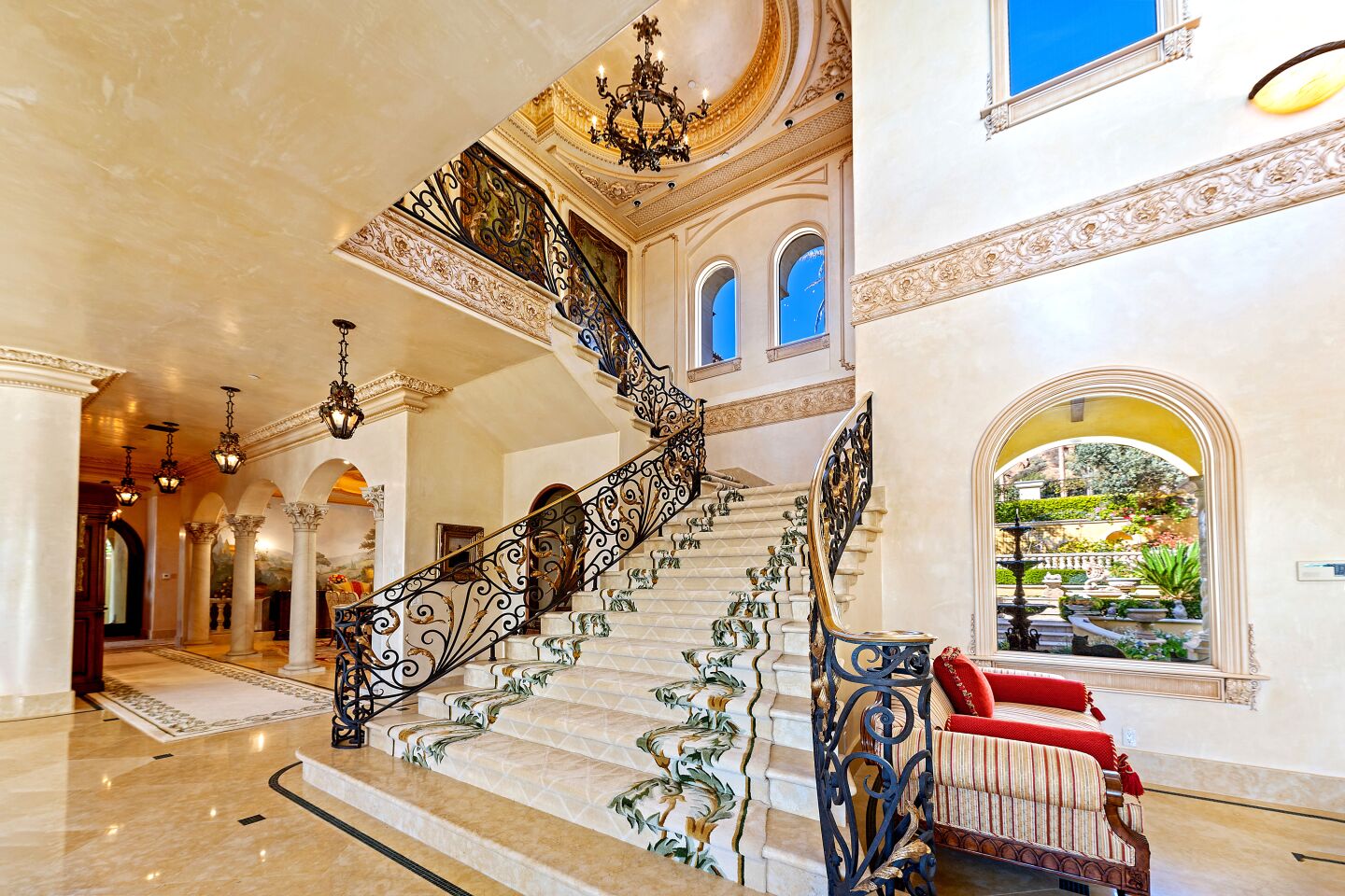 A dramatic banister and chandelier on a staircase leading to the second floor.