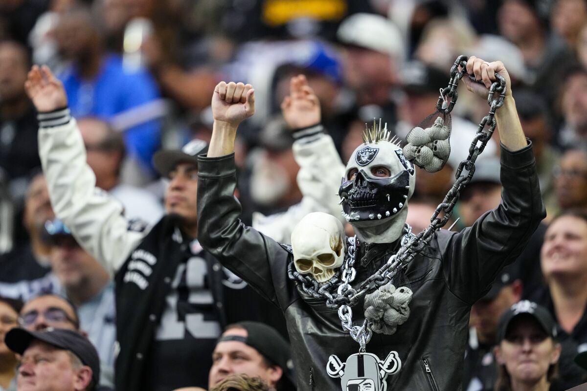 Las Vegas Raiders fans, including one in an elaborate costume, cheer in the stands