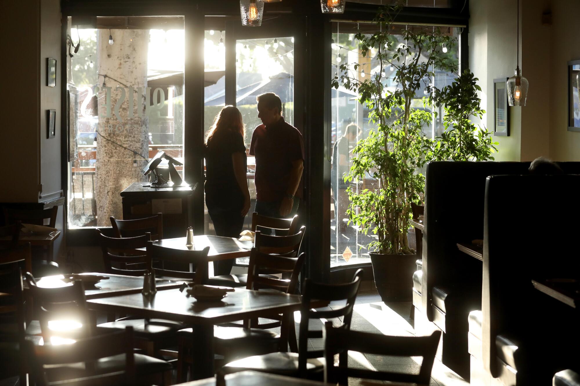 Rob and Karen Serritella, co-owners of Louise's Trattoria, wait for customers at the front door of the restaurant.