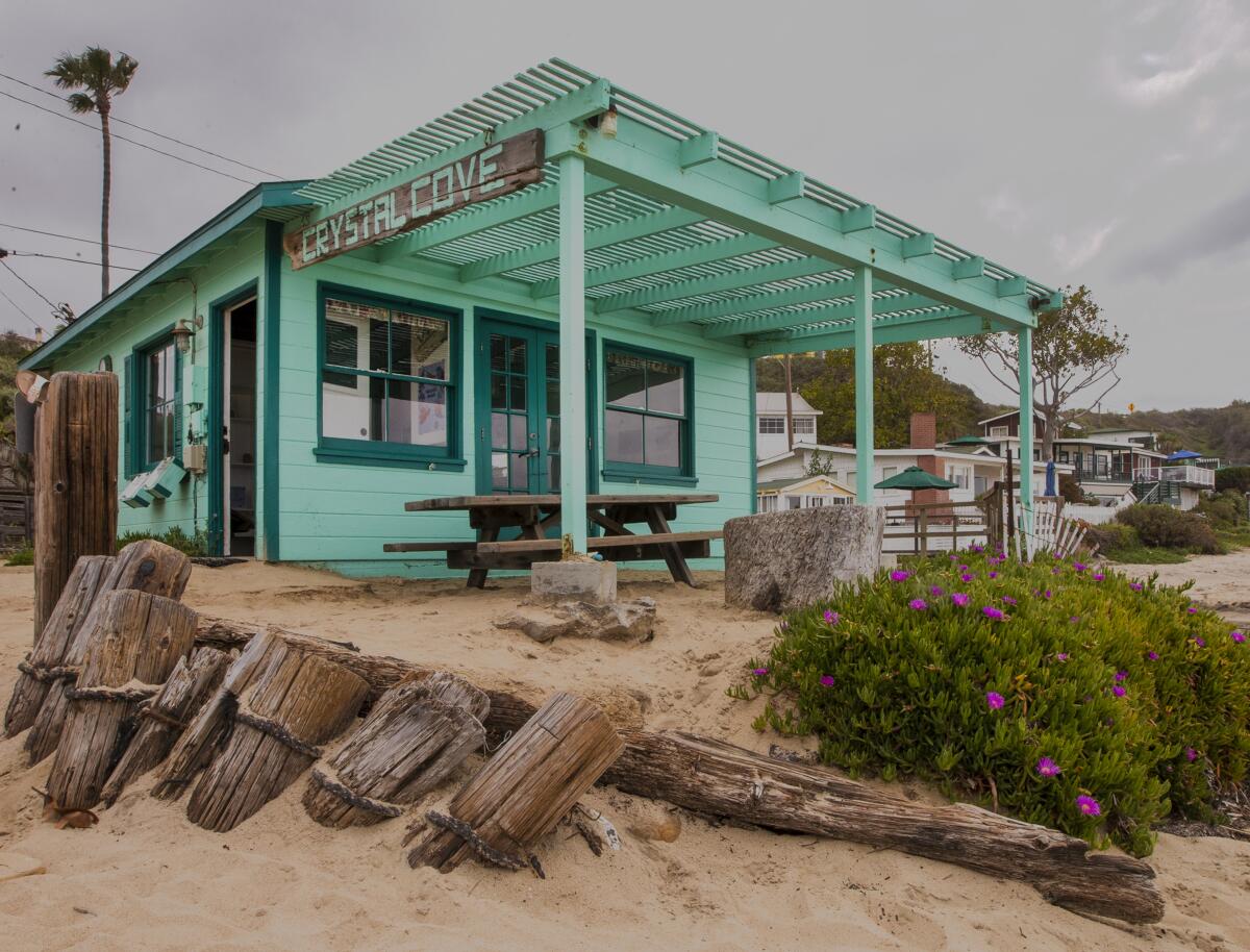 A green beach cottage with a sign that reads "Crystal Cove."