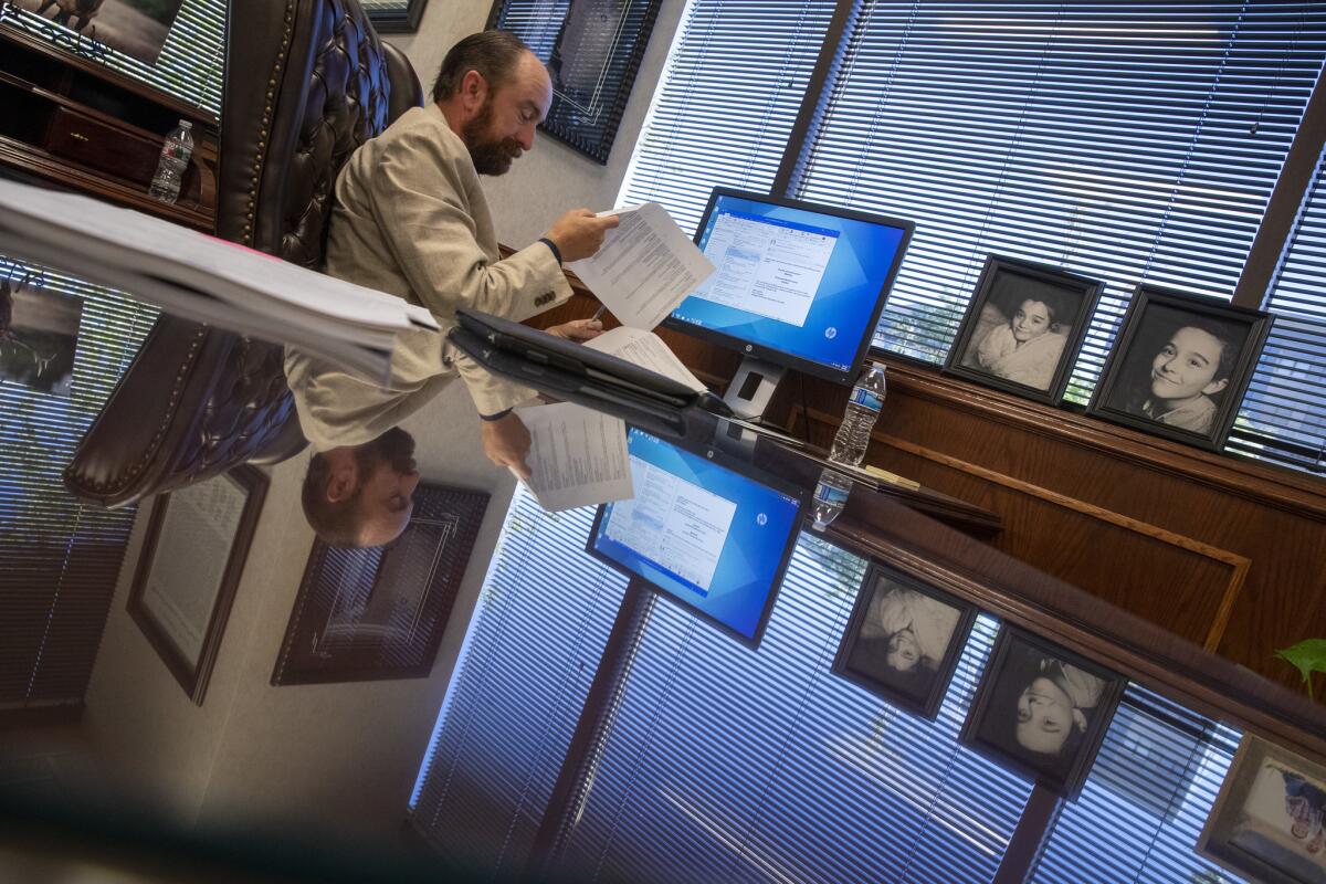 With portraits of his two children reflected on his desk, Utah County commissioner Nathan Ivie, a prepares for a commission meeting in his office in Provo, Utah. (Brian van der Brug / Los Angeles Times)