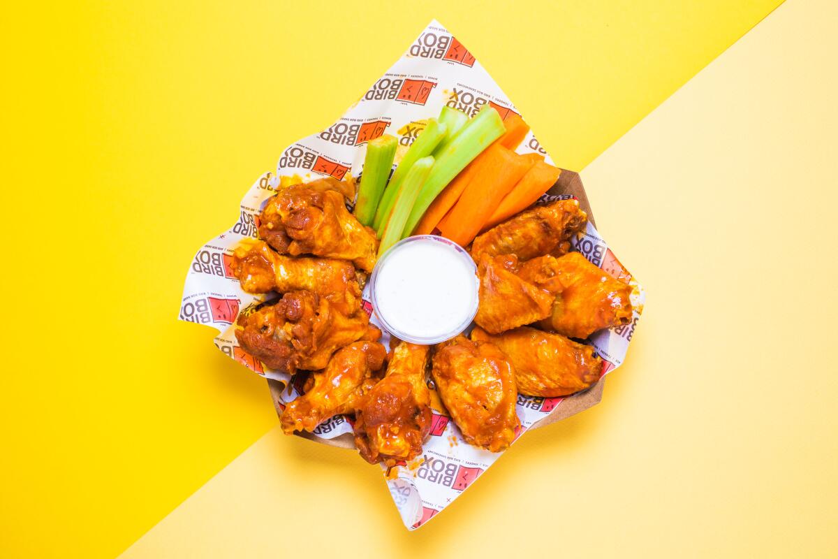 A plate with a circle of chicken wings, celery sticks and carrot sticks around a container of ranch dressing