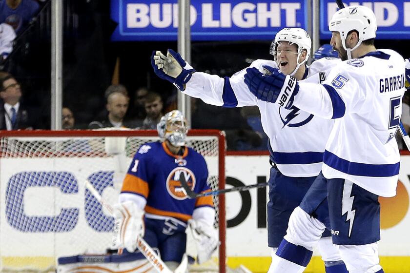 Lightning defenseman Jason Garrison (5) and left wing Ondrej Palat celebrate after Garrison scored the winning-goal in overtime against Islanders goalie Thomas Greiss on Friday night.