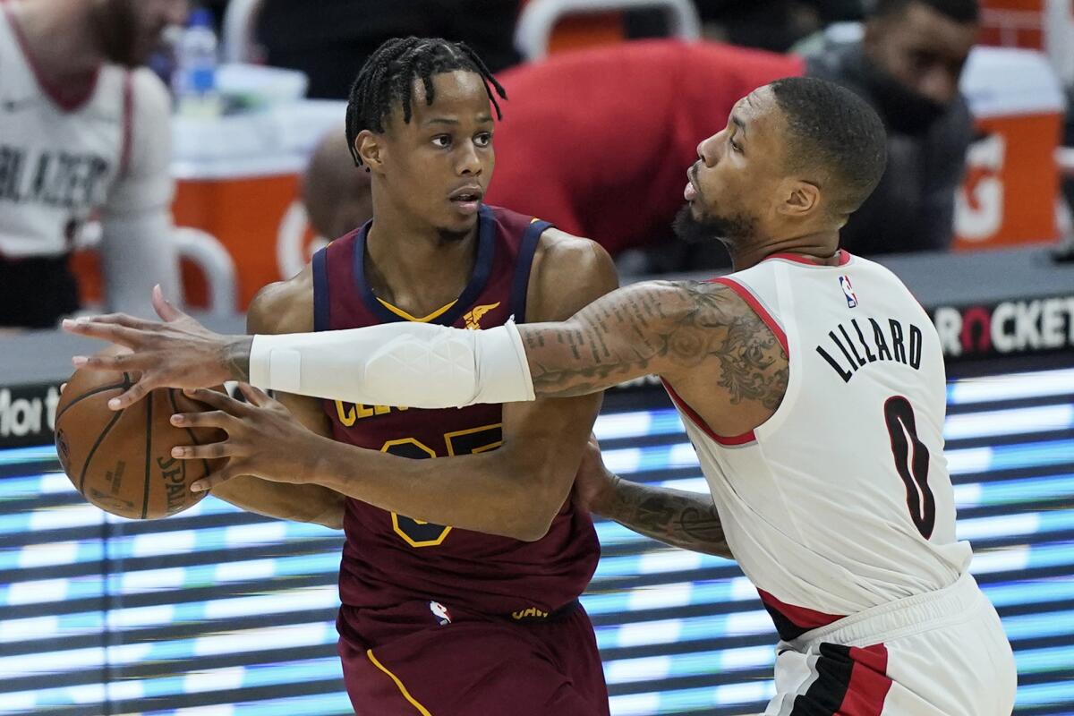 Portland Trail Blazers' Damian Lillard (0) defends against Cleveland Cavaliers' Isaac Okoro during the second half of an NBA basketball game Wednesday, May 5, 2021, in Cleveland. (AP Photo/Tony Dejak)