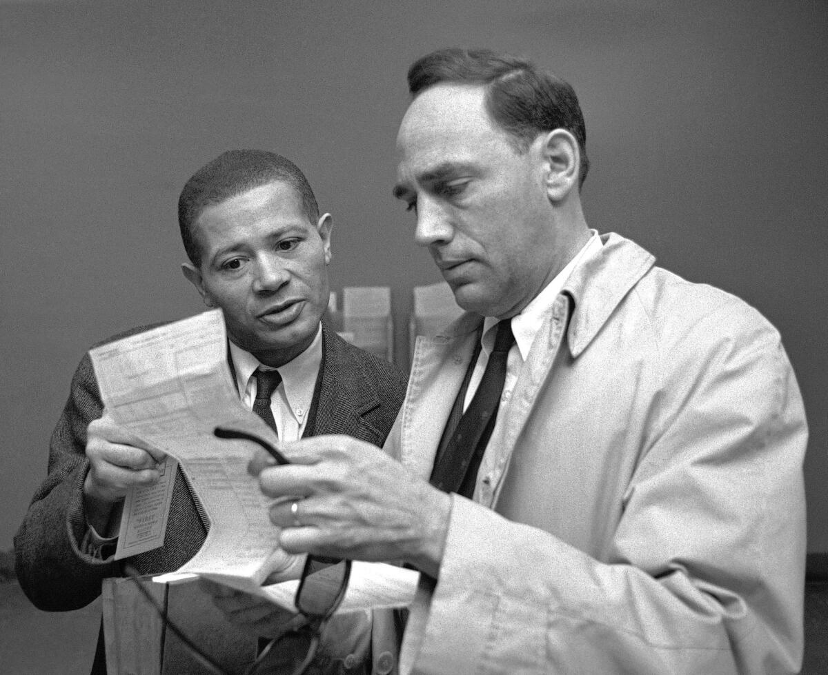 In a photograph from April 16, 1964, Willaim Worthy, left, and attorney William Kunstler look over Worthy's application for a new U.S. passport. Worthy's passport had been revoked after he defied State Department restrictions and traveled to China for a reporting trip in 1956.
