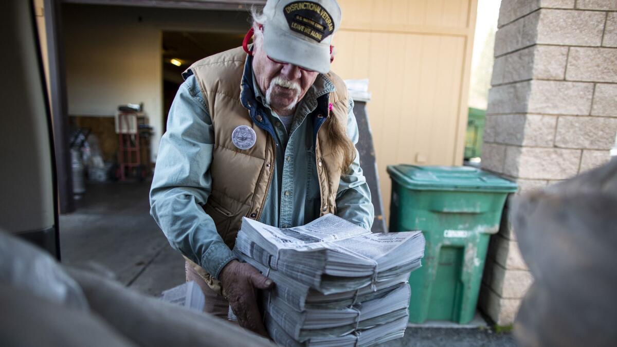 Scott McDermid loads freshly printed copies of the Mountain Messenger into the trunk of a car for distribution.