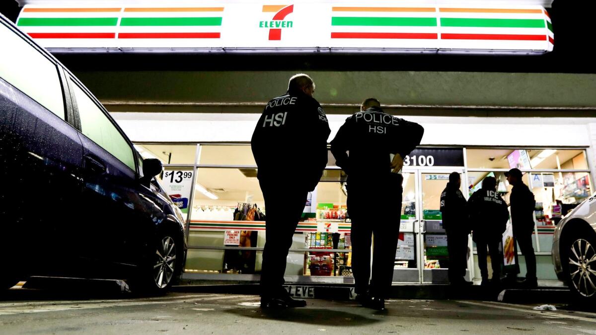 Federal immigration agents serve an employment audit notice in January at a 7-Eleven convenience store in Los Angeles.