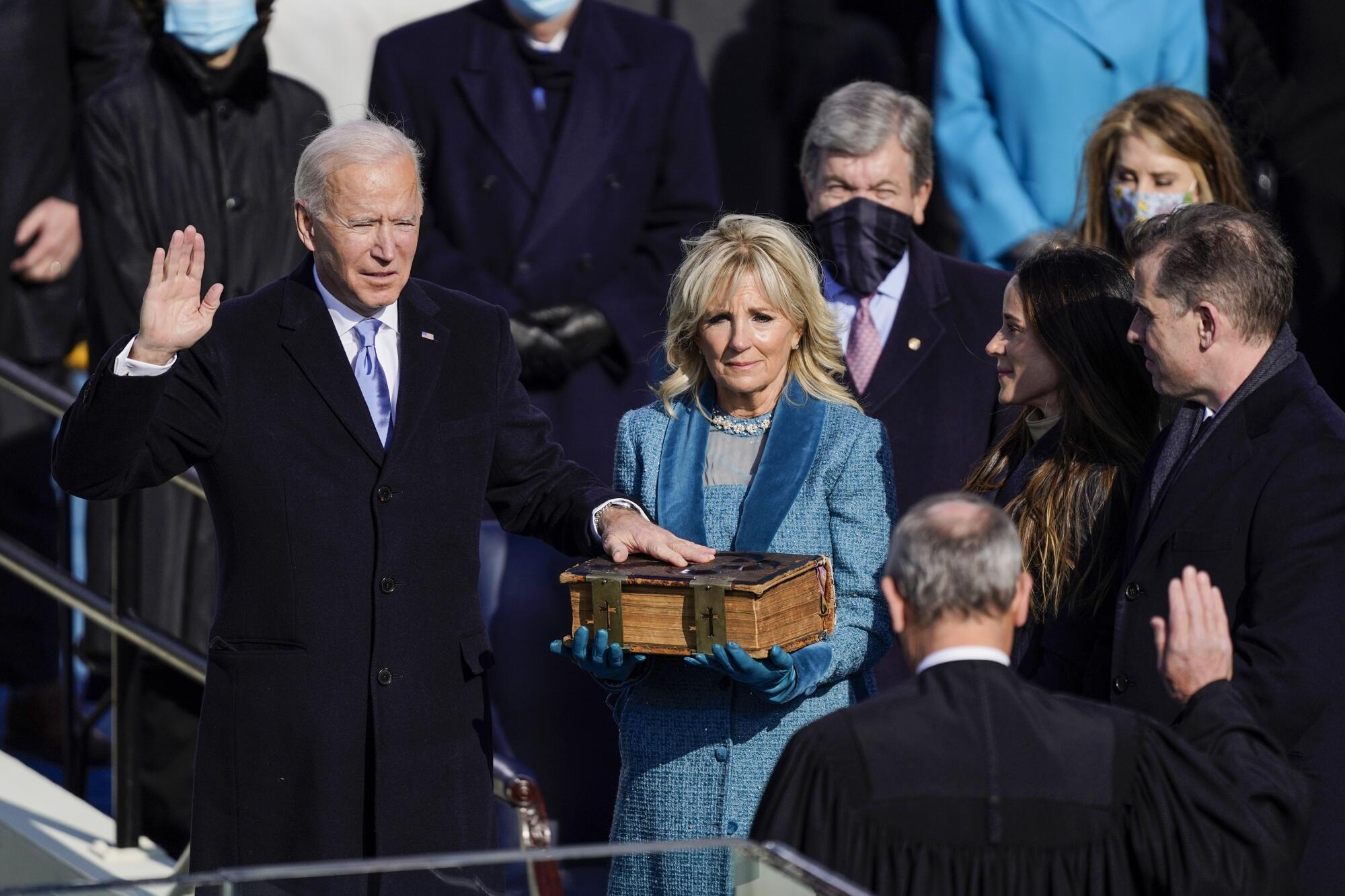 President Biden raises his right hand as his left rests on a Bible held by his wife, Jill 