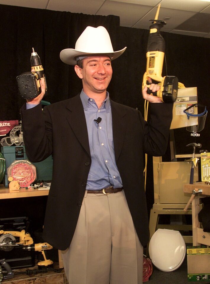Jeff Bezos, founder and CEO of Amazon.com, demonstrates a cordless power drill and reciprocating saw as he wears a western-style hard hat at a New York news conference, Tuesday, Nov. 9, 1999.