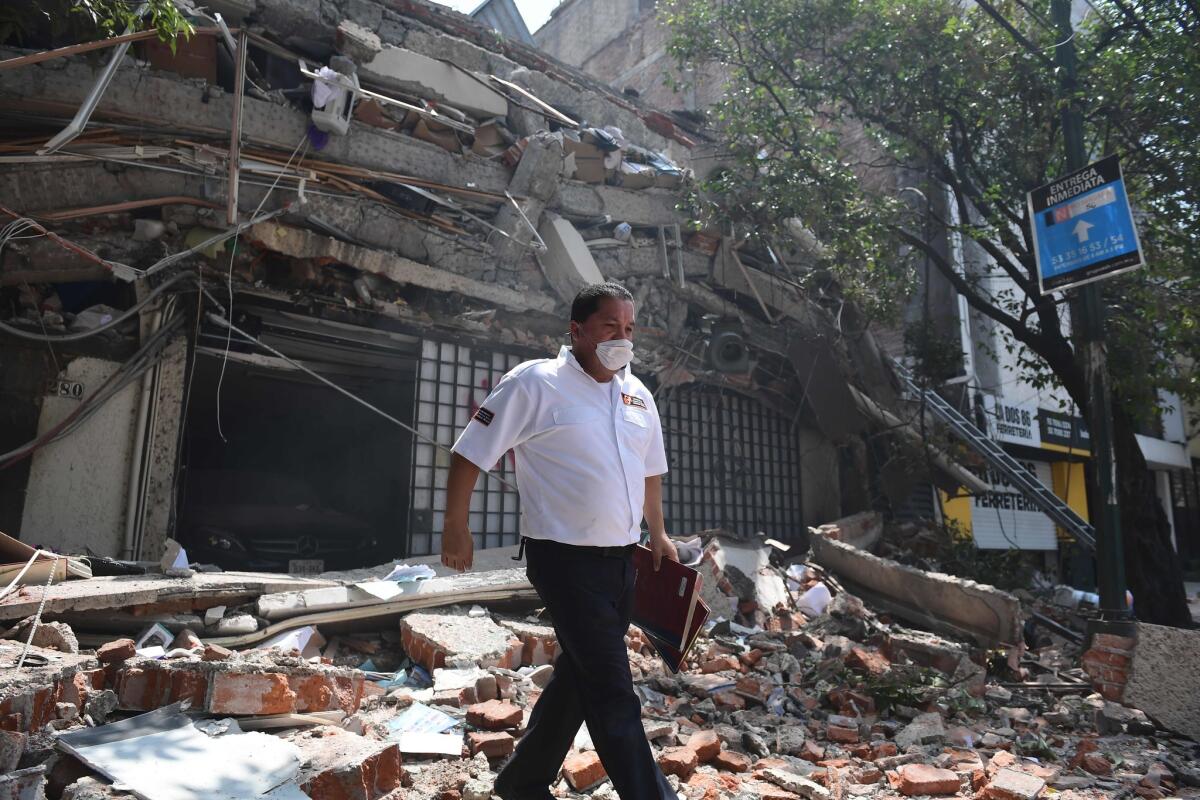 A security guard walks over debris of a collapsed building in Mexico City.