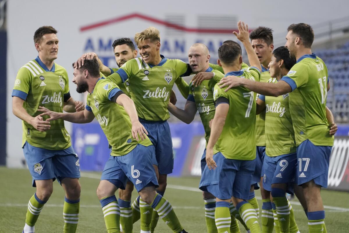 Seattle Sounders midfielder Joao Paulo, second from left, is greeted by teammates after he scored a goal against Minnesota United during the second half of an MLS soccer match, Friday, April 16, 2021, in Seattle. (AP Photo/Ted S. Warren)