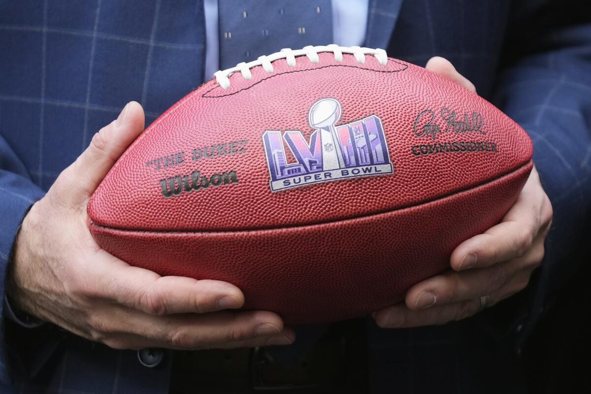 Nevada Republican Gov. Joe Lombardo holds an NFL football with the Super Bowl LVIII logo on it.