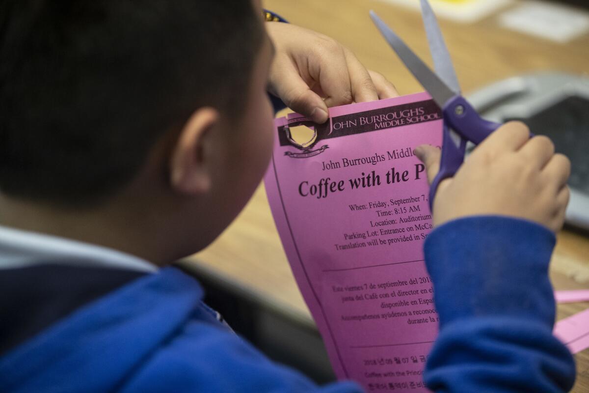 A Burroughs Middle School student in a class for students with special needs cuts out a flyer.